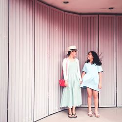 Smiling woman with daughter standing by wall