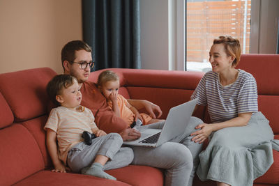 Big happy family watching movies playing games on laptop. mother father kids spending time with