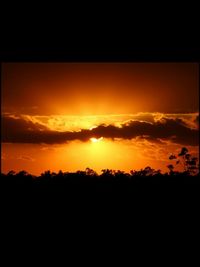 Silhouette landscape against dramatic sky during sunset