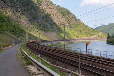Train on railroad track by mountain against sky