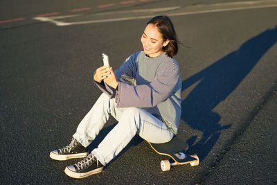 Side view of young woman sitting on road