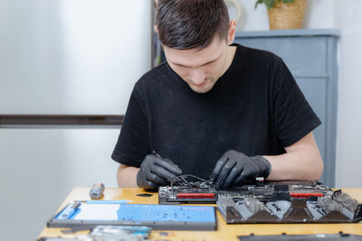 A young man repairs a computer at home.