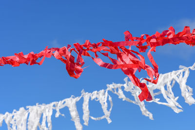 Vivid red and white ribbons prepared for a religious festival swaying in the wind with blue sky