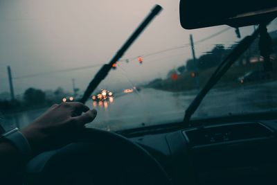 Person holding umbrella seen through car windshield