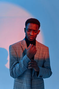 Young man standing against colored background