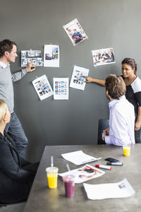 Mid adult businesswoman giving presentation over photograph to colleagues in office