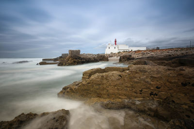 Lighthouse by sea against sky