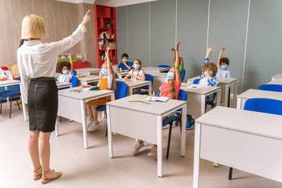 Cute kids wearing mask raising hands at hospital