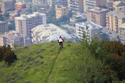 Rear view of woman riding bicycle on hill against buildings