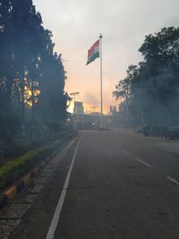 Road by trees against sky in city