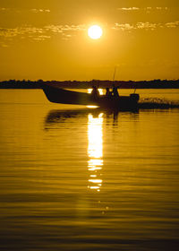 Silhouette boats in lake against orange sky