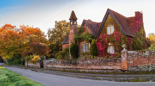 Old building by trees against sky during autumn