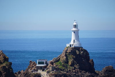 Lighthouse by sea against sky