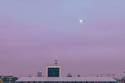 Low angle view of illuminated buildings against sky at dawn