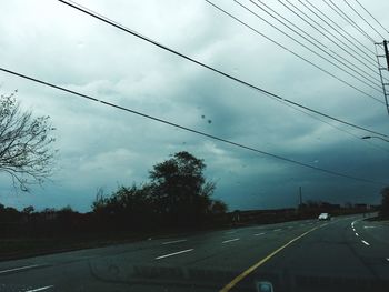 Road by trees against sky