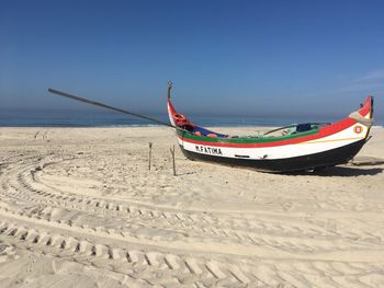 Boat moored on beach against clear sky