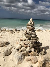 Stack of pebbles on beach against sky