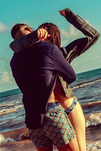 Couple romancing while standing on shore at beach