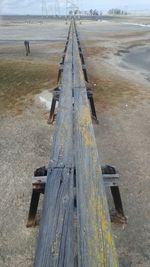 High angle view of old wooden footbridge at sandy beach