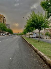 Street amidst trees and buildings against sky