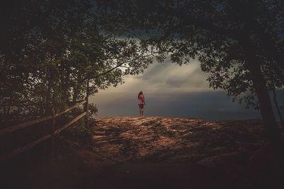 Rear view of woman standing by tree against sky