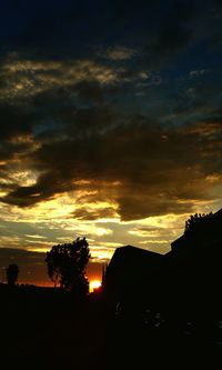 Silhouette of trees against cloudy sky