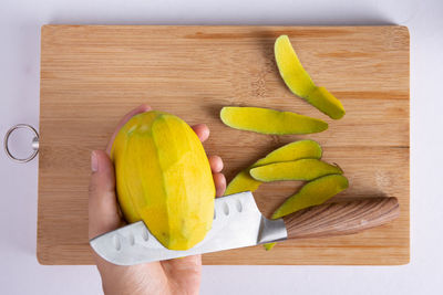 Close-up of hand holding banana leaf on cutting board