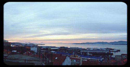 View of harbor against cloudy sky at sunset