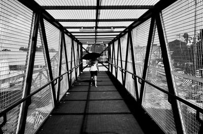 Rear view of woman walking on footbridge