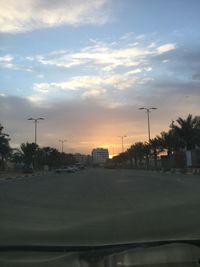 Street by city against sky during sunset