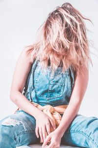 Woman with tousled hair sitting against white background