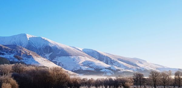 Snowcapped mountains against clear blue sky