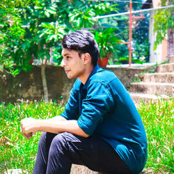 Side view of young man sitting on land