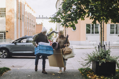 Mature couple with luggage walking together on footpath
