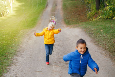 Smiling siblings running on footpath