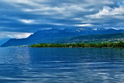 Scenic view of lake by mountains against sky