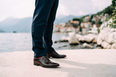 Low section of man standing on shore