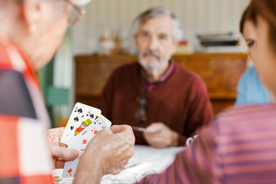 Cropped image of senior woman playing cards with family at home