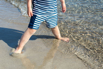 Low section of girl standing at sandy beach