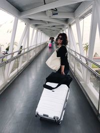 Portrait of woman with suitcase on footbridge