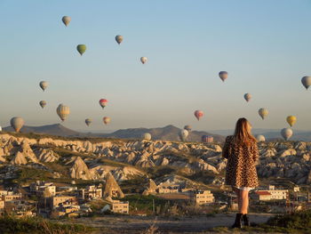 Rear view of woman with hot air balloons flying in sky