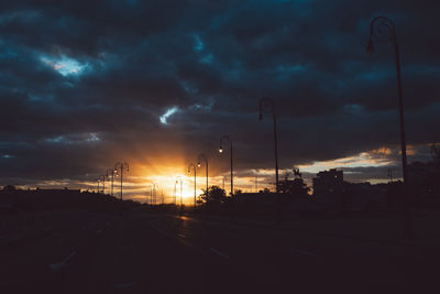 Cars on road against dramatic sky during sunset