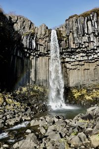 Scenic view of waterfall and volcanic stone