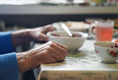 Close-up of senile sinewy hands at the dinner table.