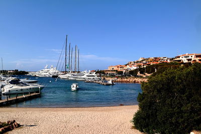 Sailboats moored at harbor against clear blue sky