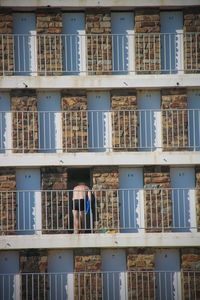 Rear view of shirtless mature man standing in balcony