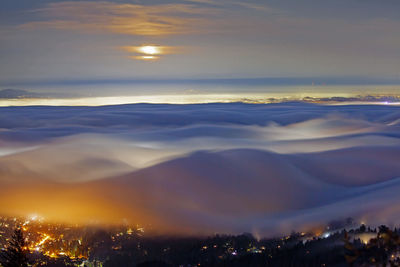 Aerial view of illuminated cityscape against sky during sunset