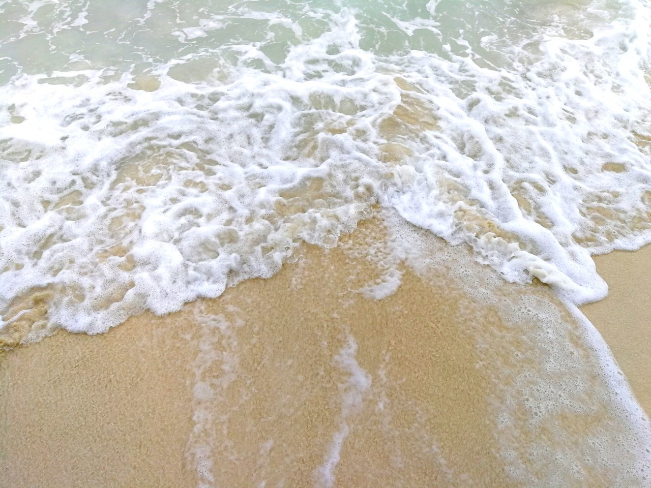 HIGH ANGLE VIEW OF WAVE RUSHING TOWARDS SHORE