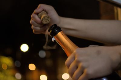 Cropped hand of woman opening prosecco