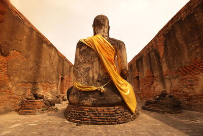 Buddha statue amidst wall at ayutthaya kingdom against clear sky